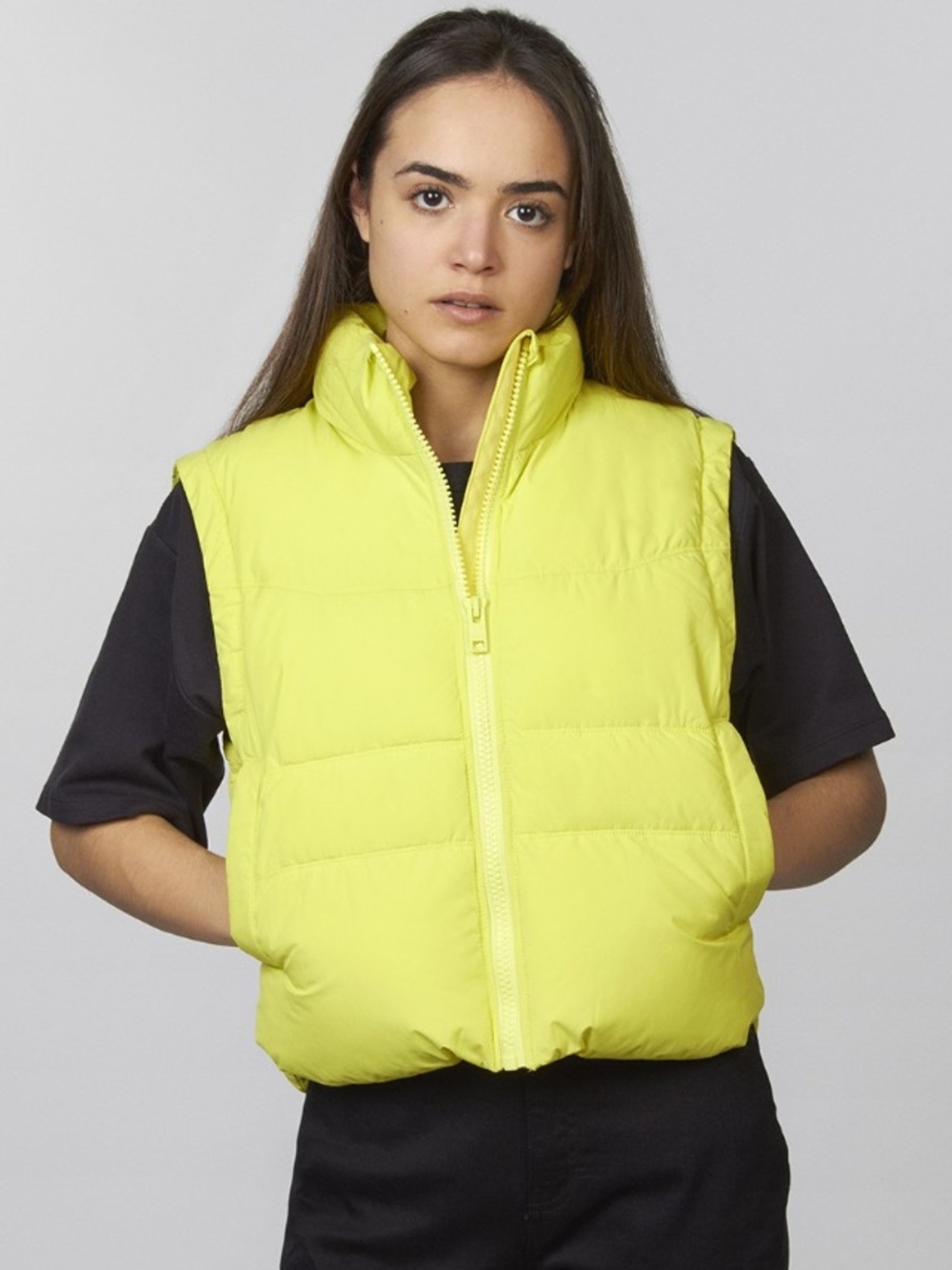 light yellow sleeveless puffer vest with a full zipper closure and side pockets.